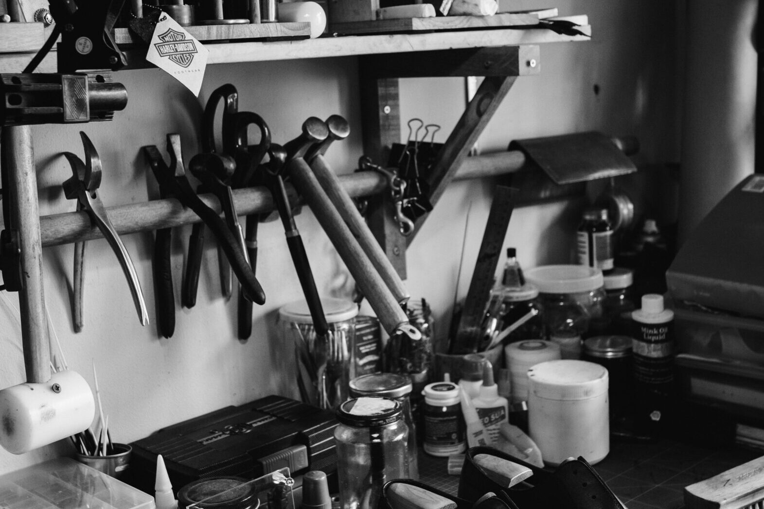 Explore a traditional shoemaker's workshop filled with tools and crafted shoes, captured in classic black and white.